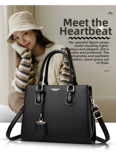 Close-up of black lychee grain leather handbag with gold hardware and shoulder strap