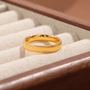 Minimalistischer goldener Titanstahlring mit Textur in einer edlen Schmuckschatulle
