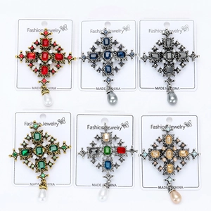 Detail view of baroque cross brooches with teardrop pearls in six assorted vintage colors