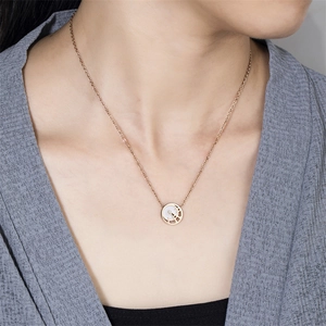 Détail du collier en titane or rose avec incrustation de nacre blanche et motif en H