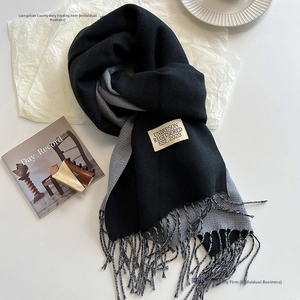 Detail of double-sided cashmere-like scarf with fringe edges and woven logo label