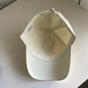 Inside view of a cream cotton baseball cap showing six-panel structure and metal buckle
