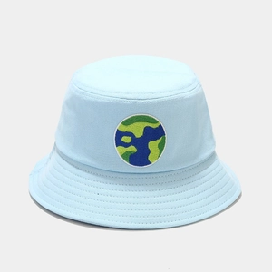 Detail of light blue cotton bucket hat with circular embroidered patch and stitched brim