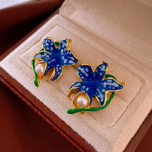 Macro detail of vintage blue flower earrings with pearl center and gold leaf accents