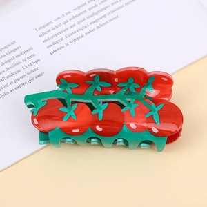 Detail der tomatenförmigen Haarklammer mit glänzender roter und grüner Acetat-Oberfläche