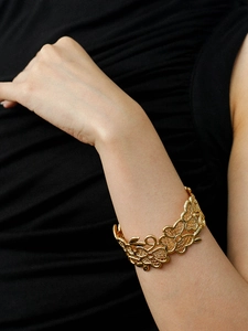 Detailed close-up of 18k gold plated hollow flower cuff bracelet on a female wrist