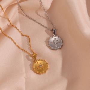 Detail of gold and silver star compass pendant necklaces on soft silk fabric background