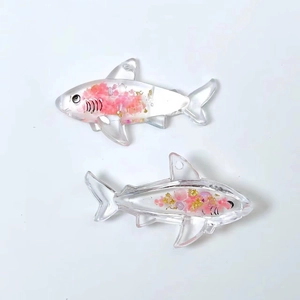 Macro shot of shark resin charms with pink dried flowers and gold flakes inside