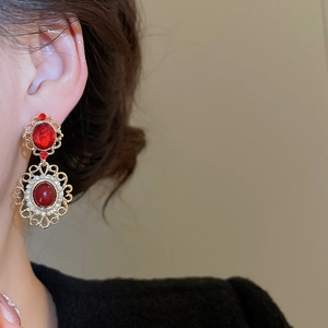 Close-up of vintage gold lace earrings with oval red stones and white zircon accents