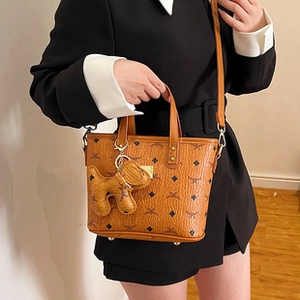 Brown leather tote bag featuring a repeating geometric pattern and cute dog bag charm