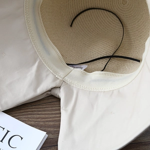 Interior view of beige straw sun hat showing texture, fabric lining and elastic strap