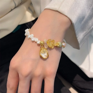 Baroque pearl and yellow crystal stone bracelet with shell charm on female wrist