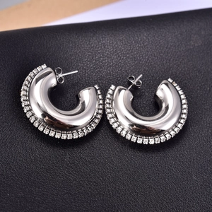 Detailed macro view of silver-tone C-shaped hoop earrings with sparkling zircon borders