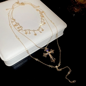 Close-up of golden layered necklace with sparkling star charms and rhinestone cross pendant
