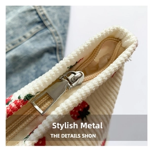 Detail of silver metal zipper on white corduroy bag with red strawberry print