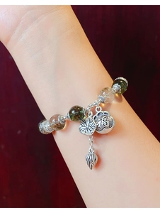 Close-up of green moss agate bead bracelet with silver lotus and Fu character charms