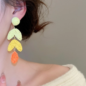 Detail of colorful hand-woven raffia drop earrings with vivid summer tassel textures
