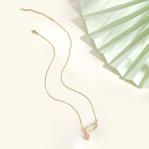 Detail view of pink heart zircon pendant on golden safety pin chain with lobster clasp
