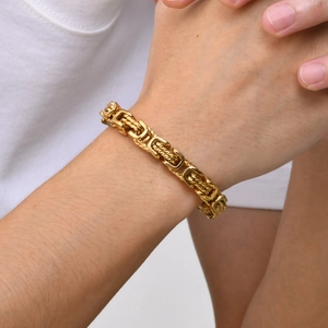 Close-up of a heavy Byzantine chain bracelet in gold finish worn on a male wrist