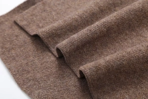 Dettaglio del poncho in maglia marrone che mostra la morbida texture in cashmere e lana