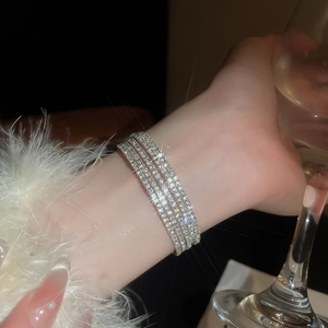Dettaglio del bracciale elastico a quattro file di strass argentati indossato da un modello