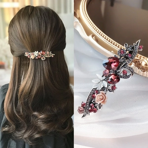 Détail macro d'une pince à cheveux paon vintage avec strass rouges et fleurs