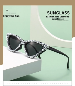 Detail of elegant cat-eye sunglasses featuring white faux pearl embellishments on the frame
