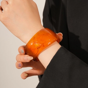 Macro shot of amber resin bangle showing natural marble texture and high-polish finish
