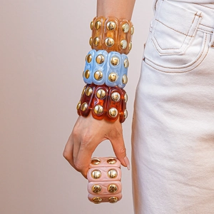 Detail view of wide acrylic bangle with marble texture and golden dome rivets