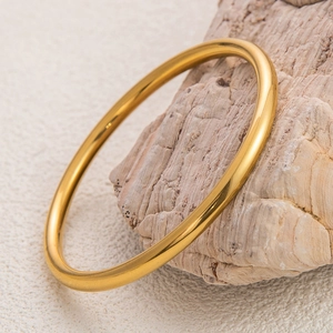 Close-up of a 18K gold plated minimalist bangle with a polished mirror finish on stone