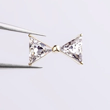 Macro shot of 3D bow nail charm with gold base and clear triangular gemstones