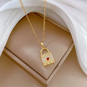 Luxurious gold heart lock necklace with white crystals and red gemstone on silk