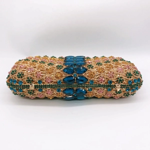 Macro view of colorful rhinestones and blue gemstones on golden hollow evening bag