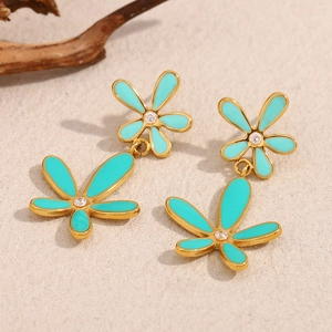 Macro view of floral double-layer earrings in 18K gold plated finish with teal enamel