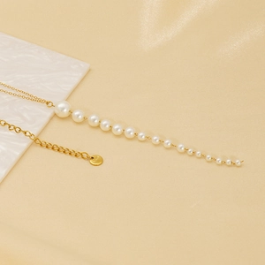 Élégant collier à pampilles en perles dorées et acier inoxydable sur marbre blanc