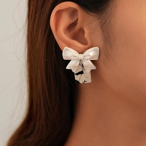 Close-up of a vintage white resin bow earring with a black marble pattern square pendant