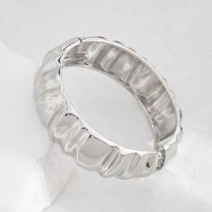 Dettaglio macro del bracciale argentato con texture ondulata irregolare e finitura lucida