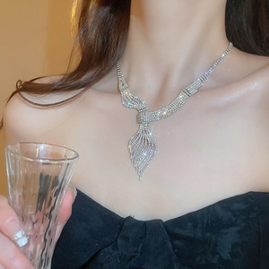 Macro shot of silver leaf tassel necklace with glittering crystals on model with glass