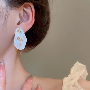Vue détaillée de boucles d'oreilles ovales avec fleurs dorées et motif papillon