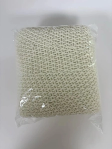Folded beige knitted Christmas tree skirt in clear plastic packaging on white background