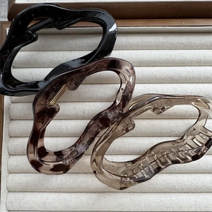 Close-up of three PC cloud-shaped hair claws in black, tortoiseshell, and amber tones