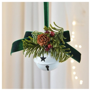 Close-up of white metal bell with dark green velvet ribbon, pine cone and red berries