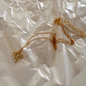 Detailed view of a gold bow pendant necklace featuring a delicate chain and lobster clasp