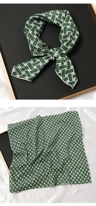 Détail d'un foulard en soie verte à motifs géométriques blancs, noué et à plat