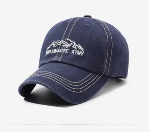Close-up of mountain embroidery and stitched brim on a navy blue washed cotton baseball cap