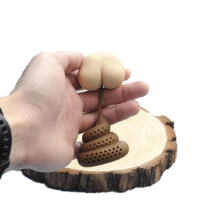 Detailed view of a novelty silicone poop tea infuser held by hand against a wood background