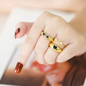 Detailed view of gold rings with blue heart stones and white zircons on model hand