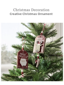 Detail of wooden Merry Christmas ornaments with Santa and reindeer clips on a tree