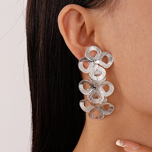 Detailed close-up of silver metal triple flower earrings with radial textured pattern