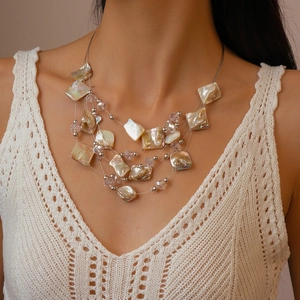 Detailed view of layered bohemian necklace with shell slices and crystal beads on model